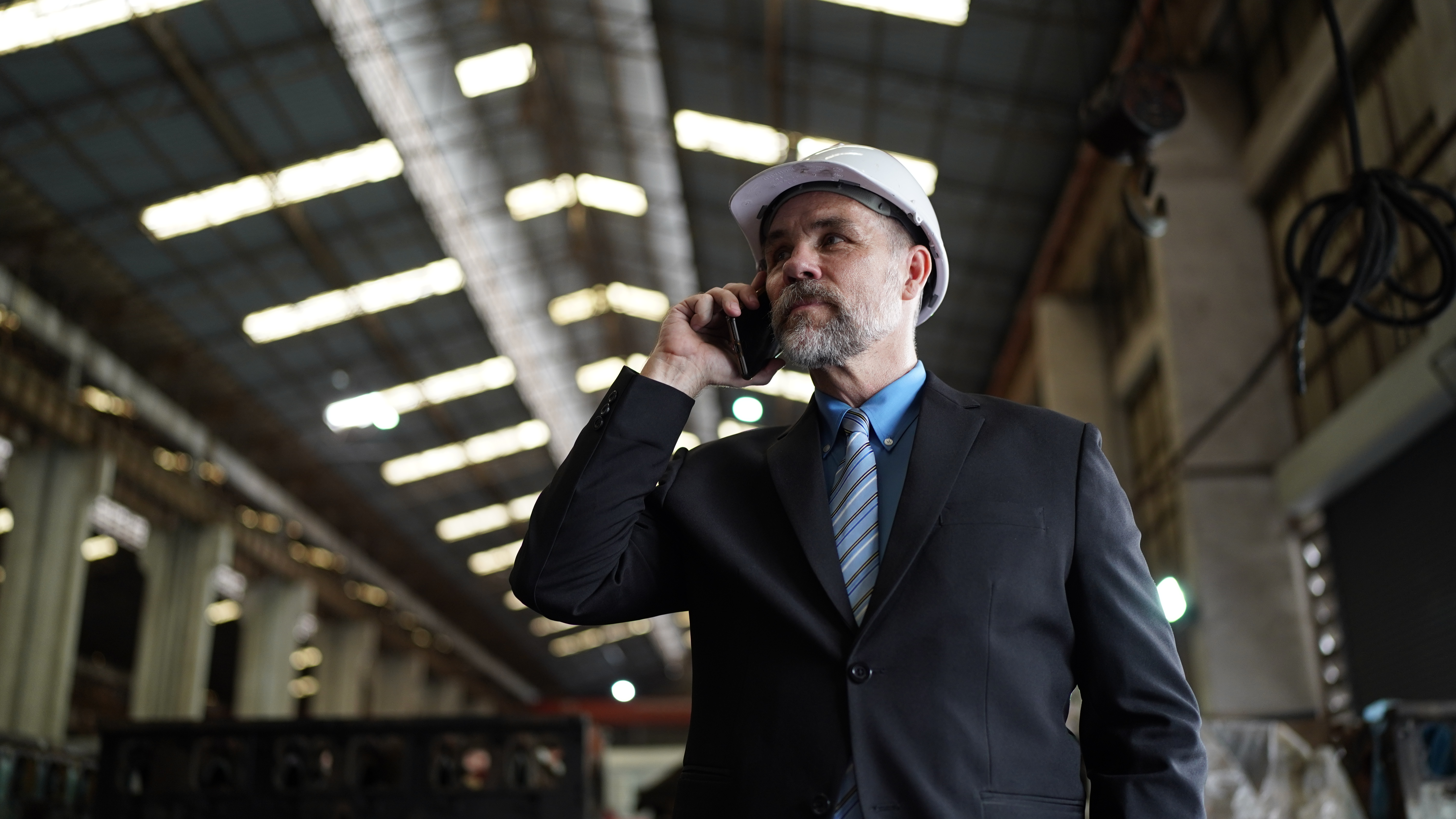 Businessman in factory warehouse is talking on mobilephone. Factory indusrty Business.